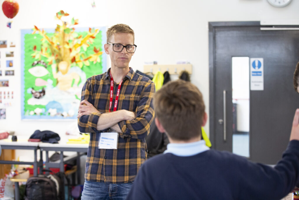 Adult facilitator in a classroom with a school student. 