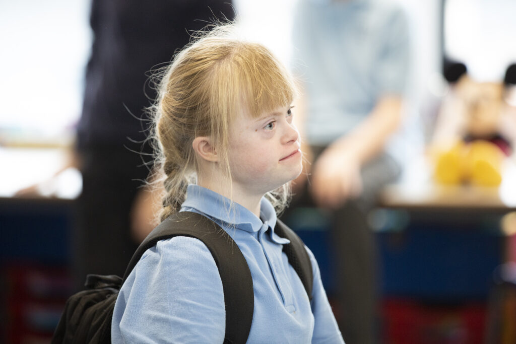 School student wearing a rucksack in a classroom. 