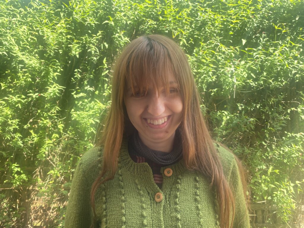 Laura Smith, new trustee at Cap-a-Pie, wearing a green cardigan with long brown hair