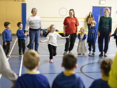 Families joining in during Marvellous Microbes session in school hall.