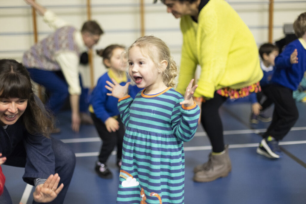 Child having fun taking part in a school workshop in school assembly hall.
